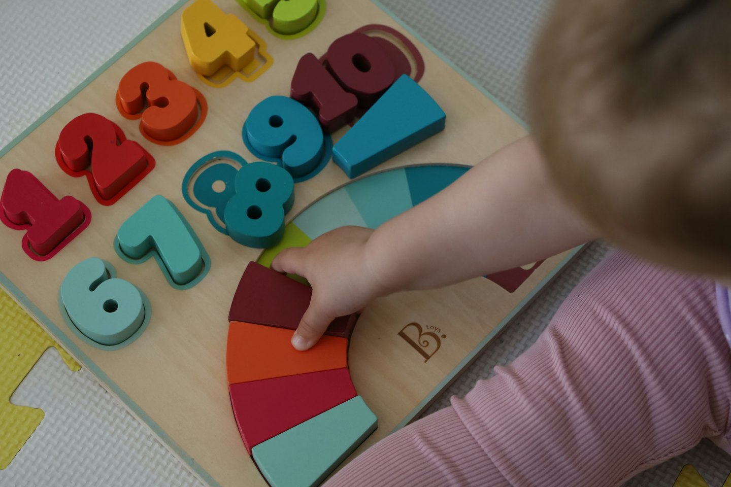 Kinderhand steckt eine Zahl in ein Steckspiel.