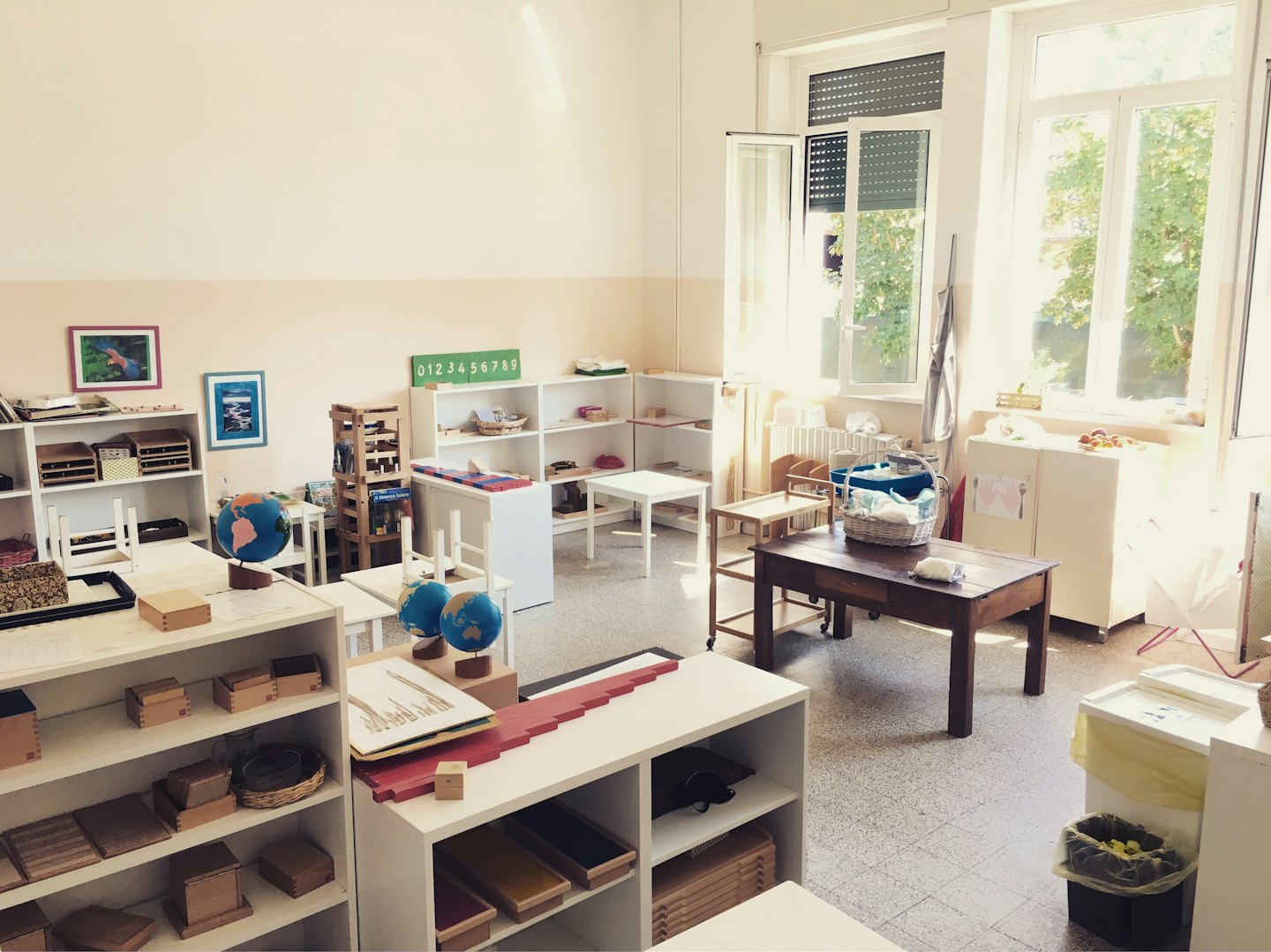 Organisierter Montessori-Klassenzimmer mit Holzspielzeug in Regalen und auf Tischen.
